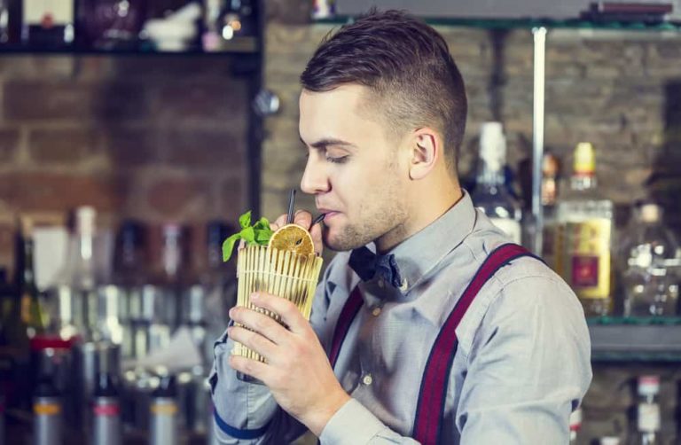 Bartender sneakily helping himself to a drink behind the bar.