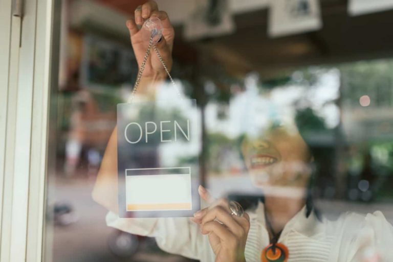 Smiling woman hanging open sign on the glass door